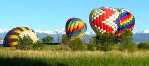 4 hot air balloons just landed, still inflated. GREAT colors. Snow covered divide in the background