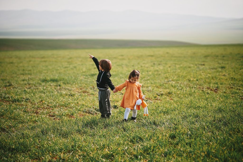 girl in orange dress walking on green grass field during daytime