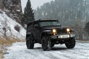 a black jeep driving down a snow covered road