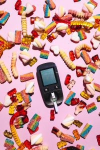 A Glucometer Surrounded by Colorful Candies