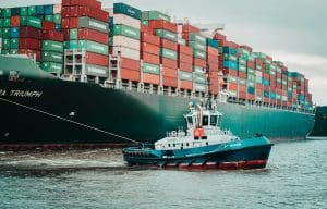 a tug boat pulling a large container ship