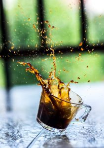 Glass cup with splash of coffee in air