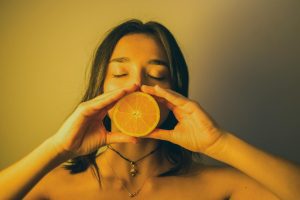 Attractive woman with eyes closed holding orange slice against lips