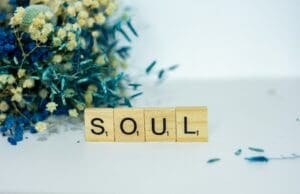 a wooden block spelling the word soul next to a bouquet of flowers