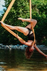 woman in black tank top and black shorts sitting on brown wooden swing during daytime