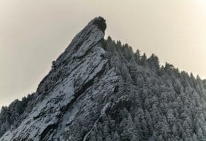 a snow covered mountain with trees on the side