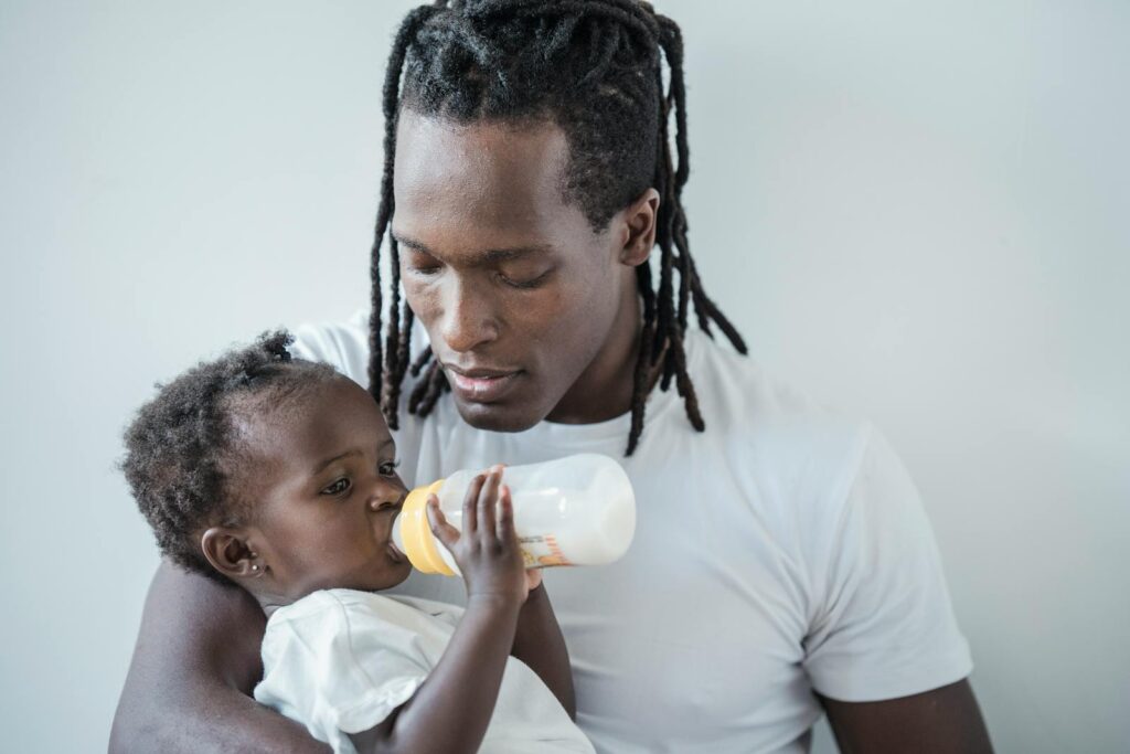 A father lovingly feeds his baby with a bottle, highlighting family bonds and warmth.