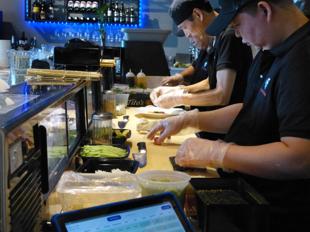 Sushi chefs hard at work behind the sushi bar. Deep concentration is evident. 