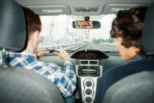 A man driving a car with another man in the back seat