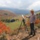 Jay Moore painting on a hill with a serene view of Colorado nature