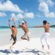 2 women in white shorts running on white sand beach during daytime