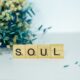 a wooden block spelling the word soul next to a bouquet of flowers